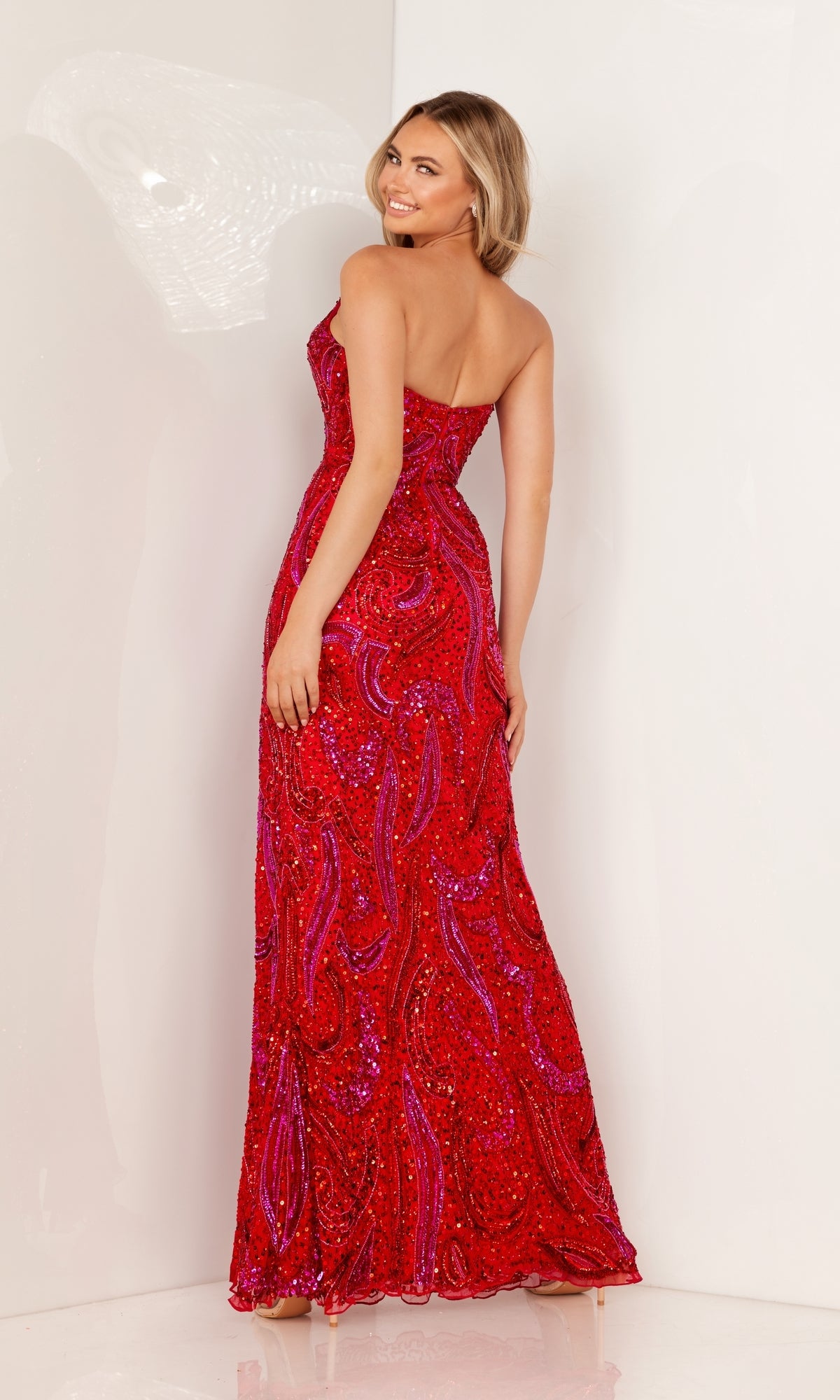 Wearing the Strapless Sequin-Print Long Prom Dress 1105, a woman stands against a white background, smiling as she looks over her shoulder and shows off the dress's fitted silhouette.